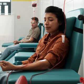 مجموعة من الأشخاص يجلسون على كراسي خضراء ويقومون بالتبرع بالدم في مركز للإسعاف