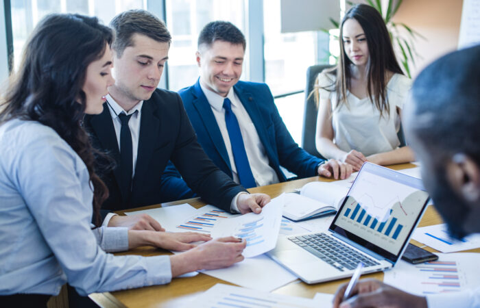 فريق عمل ضمن اجتماع في الشركة يمسكون بأوراق عليها رسمات بيانية