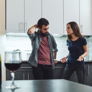 امرأة ورجل يقفان في المطبخ ويقوم الرجل بوضع يده خلف رأسه