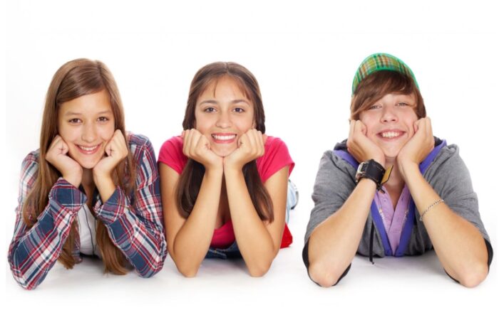 صبي وفتاتين مراهقتين يجلسون بجانب بعضهم البعض ويضعون يديهم أسفل رأسهم