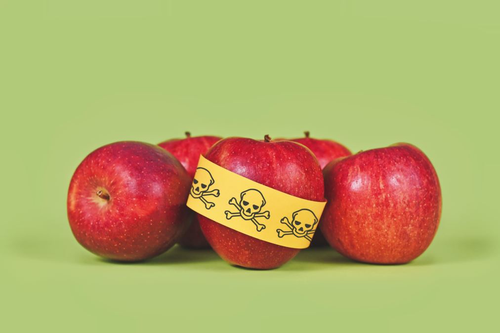 مجموعة من التفاح الأحمر ملفوف عليها شريط أصفر يدل على الخطر