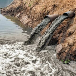 أنبوبي تصريف تلقي سائل رمادي قاتم في بحيرة اصطناعية