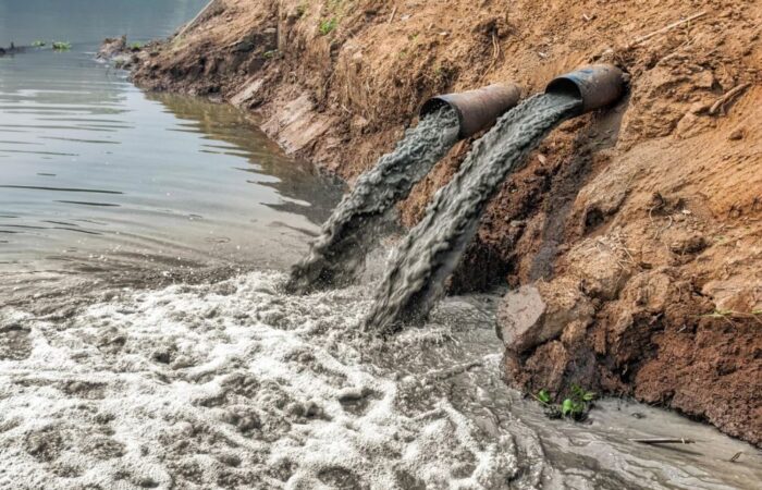 أنبوبي تصريف تلقي سائل رمادي قاتم في بحيرة اصطناعية