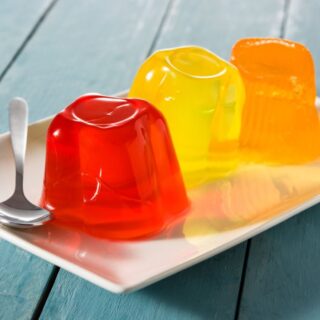 ثلاث قطع من الجيلي الملون باالبرتقالي، الأصفر والأحمر في صحن أبيض