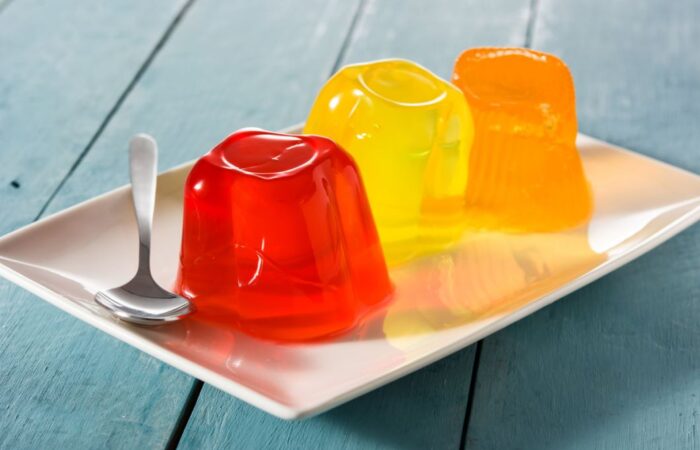 ثلاث قطع من الجيلي الملون باالبرتقالي، الأصفر والأحمر في صحن أبيض