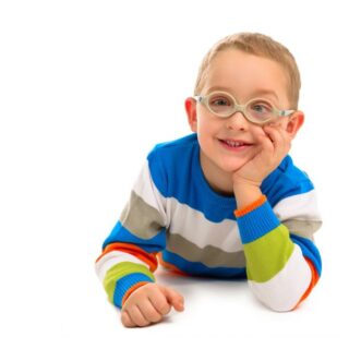 صبي مصاب بالحول يرتدي نظارات وكنزة مخططة بالأزرق والأبيض يجلس مبتسما على الأرض