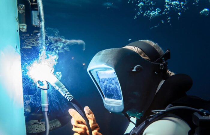 عامل في المياه يرتدي قناع للغوص ويقوم باستخدام ماكينة لحام المعادن