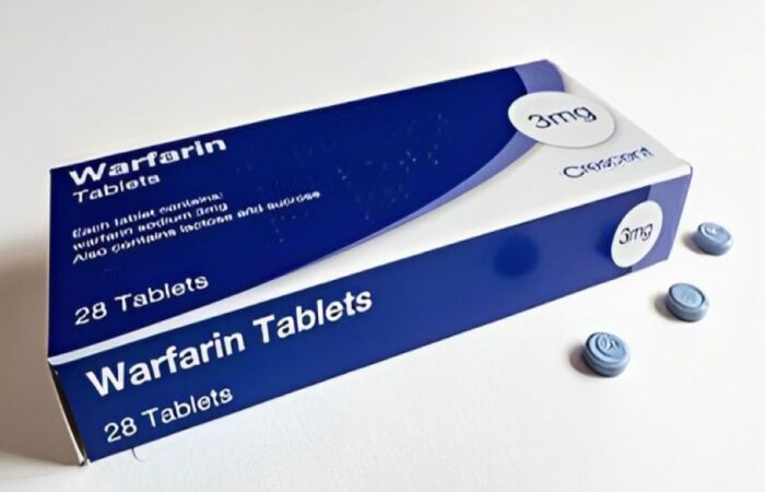 علبة دواء الوارفارين بجانبها ثلاث حبات زرقاء