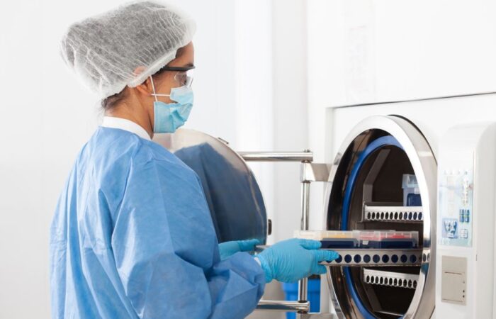 طبيبة تقوم بوضع الأدوات الطبية في جهاز يشبه الغسالة لتعقيمها