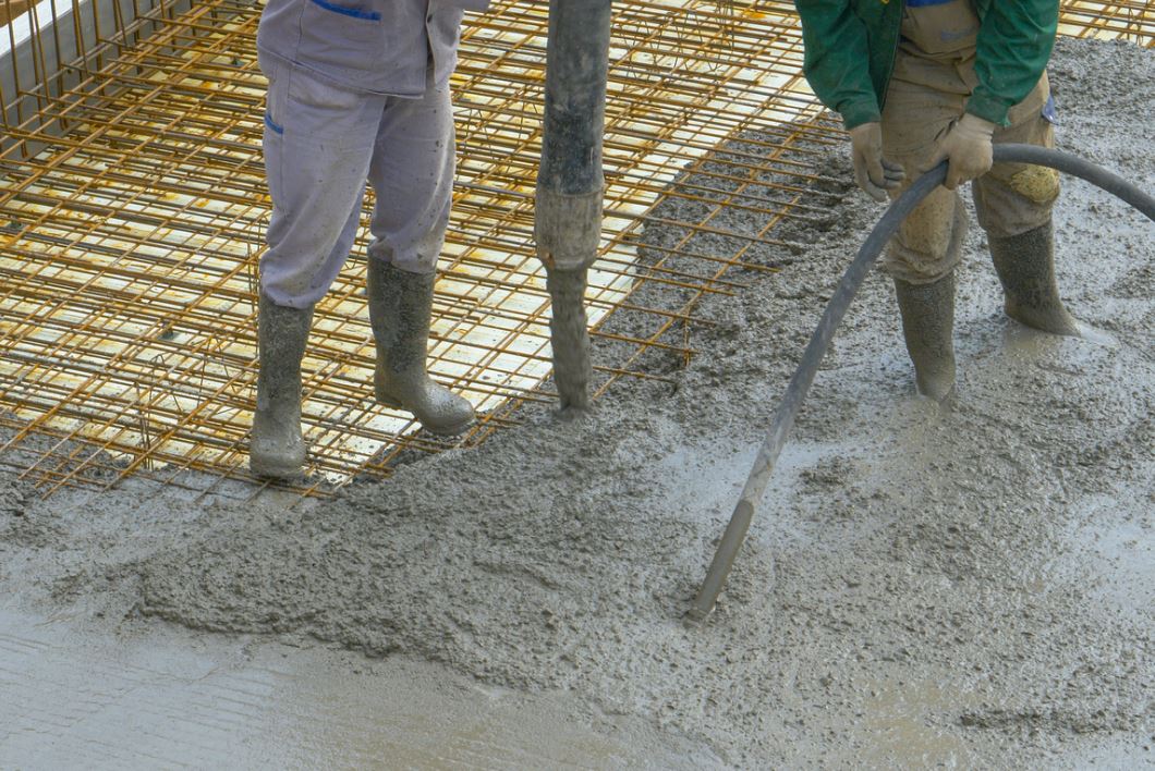 عمال بناء يقومون بصبّ الخرسانة ضمن القالب