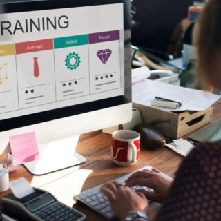 امرأة تقوم بالكتابة على لوحة المفاتيح لكمبيوتر مكتبي موجود على طاولة وعلى الشاشة تظهر كلمة تمرين مكتوبة باللغة الإنكليزية