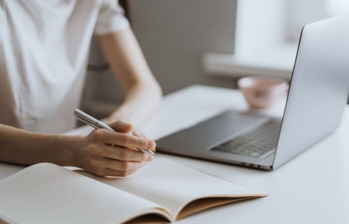 فتاة ترتدي كنزة بيضاء تدرس أمام شاشة الكمبيوتر