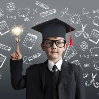 ولد صغير يرتدي ملابس التخرج السوداء مع قبعة وخلفه لوح عليه رسومات