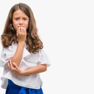 فتاة صغيرة ترتدي كنزة بيضاء تظهر خائفة وتضع أصابعها أمام فمها