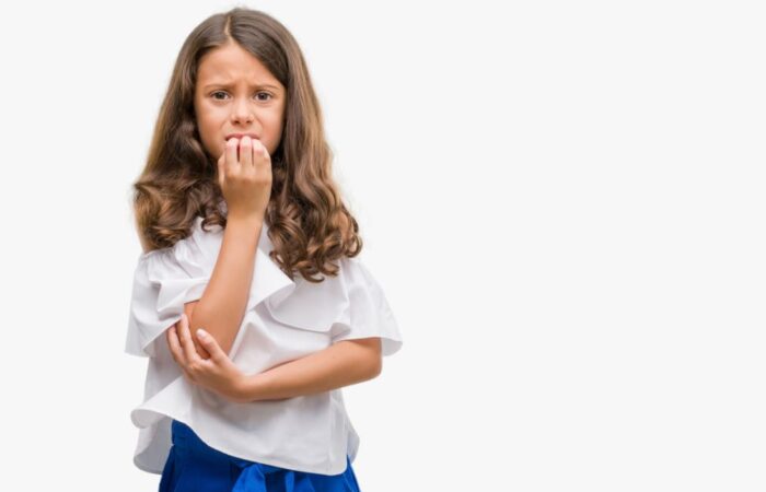 فتاة صغيرة ترتدي كنزة بيضاء تظهر خائفة وتضع أصابعها أمام فمها