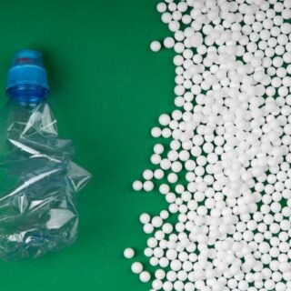 حبيبات بلاستيكية بيضاء بجانب عبوة مياه بلاستيكية فارغة