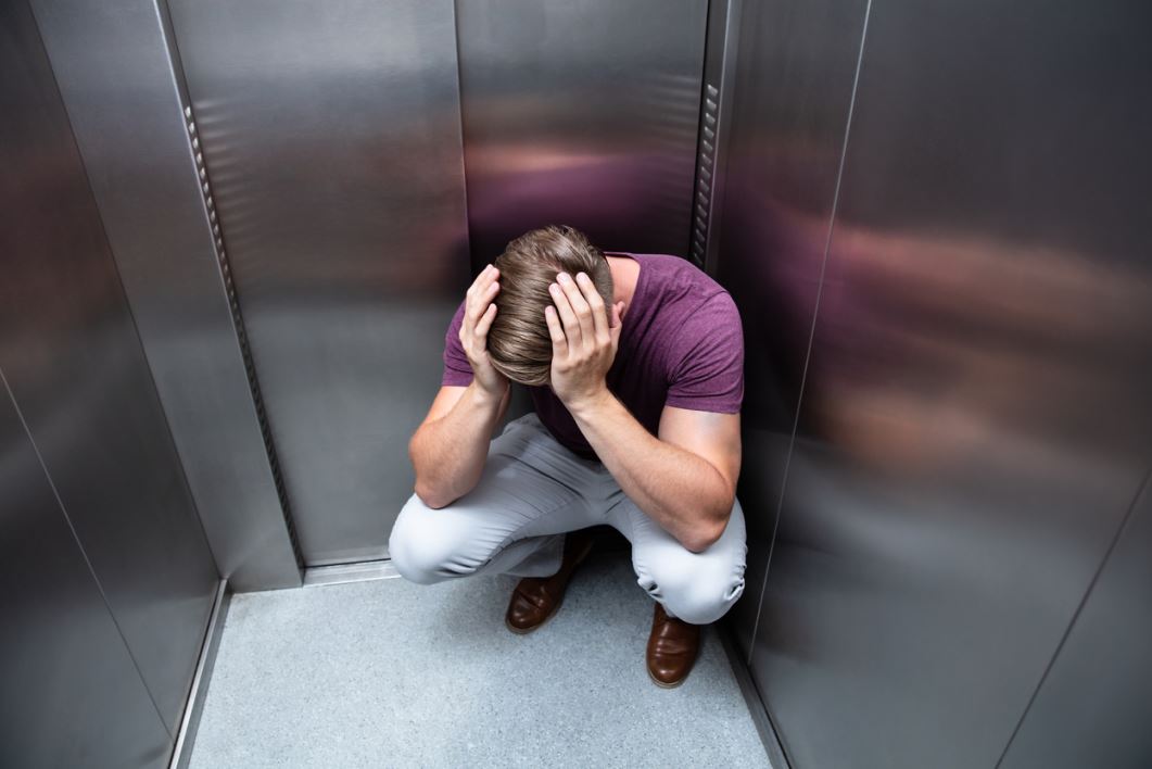 شاب يعاني من رهاب الأماكن المغلقة ويجلس خائفاً في المصعد