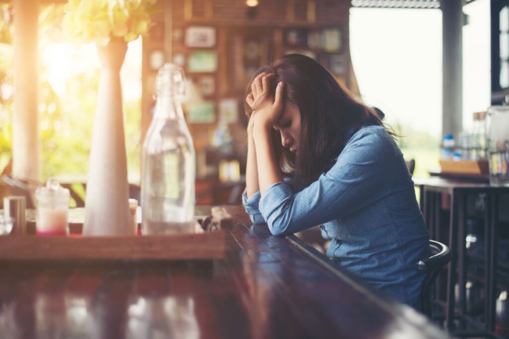 امرأة بالغة تجلس أمام طاولة وتضع يديها على جبينها