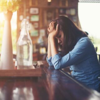امرأة بالغة تجلس أمام طاولة وتضع يديها على جبينها