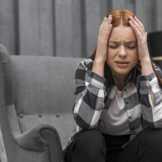 فتاة تجلس على كرسي وتضع يديها على رأسها