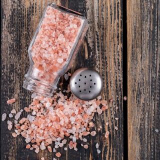 ملح صخري زهري اللون يخرج من فوهة علبة زجاجية شفافة