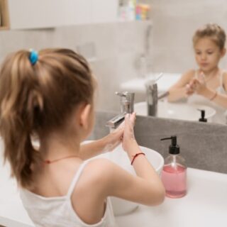 فتاة صغيرة تغسل يديها بالماء والصابون