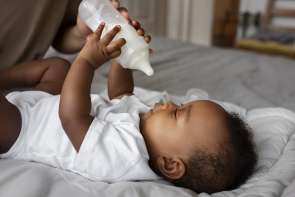 طفل رضيع يمسك زجاجة الحليب بيديه