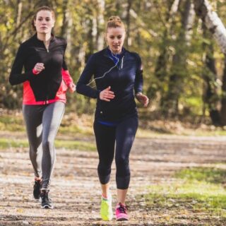 فتاتان ترتديان ملابس رياضية وتقومان بالجري في الغابة