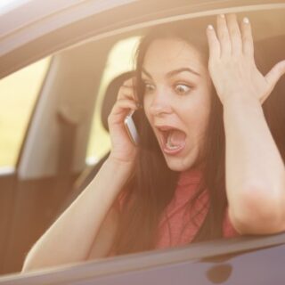 فتاة داخل سيارتها تقوم بإجراء مكالمة هاتفية وتظهر فمها مفتوح وعيونها جاحظة