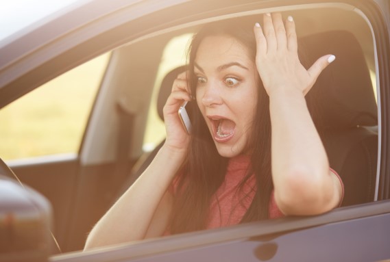 فتاة داخل سيارتها تقوم بإجراء مكالمة هاتفية وتظهر فمها مفتوح وعيونها جاحظة