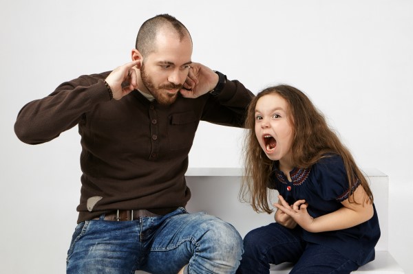 فتاة تصرخ بقوة ورجل بجانبها يضع أصابع يديه داخل أذنيه