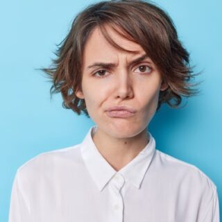 فتاة ترتدي قميص أبيض تقوم برفع أحد حواجبها