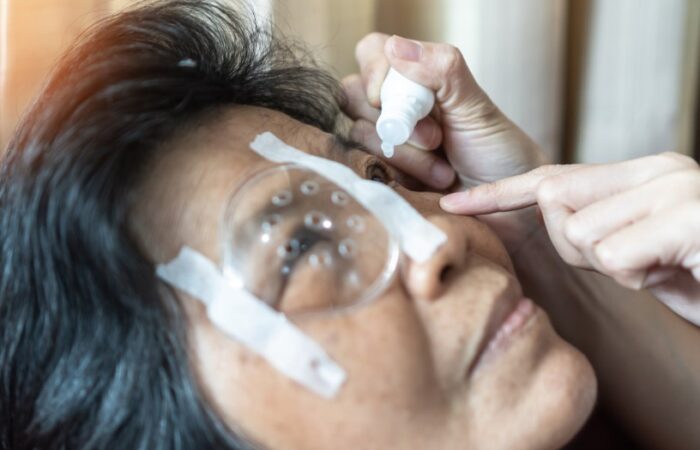 شخص يقوم بقطر قطرة في عين مريضة تضع فوق العين الثانية قطعة بلاستيكية واقية