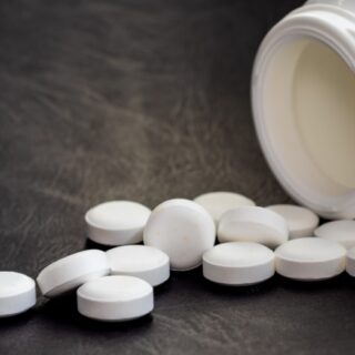 حبوب دواء بيضاء اللون بجانب علبة واء