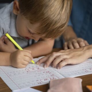 طفل أشقر يكتب أحرف باللغة الإنكليزية على الدفتر