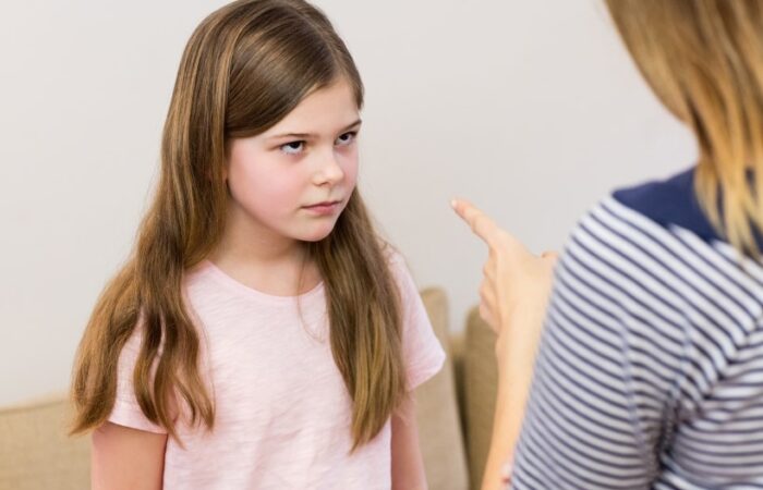 امرأة توجه إصبعها اتجاه فتاة صغيرة شعرها بني وطويل