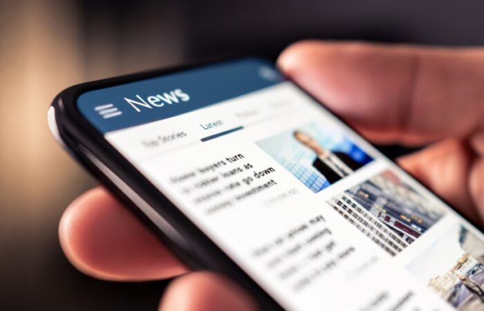 شخص يحمل هاتف ذكي مفتوح تطبيق الأخبار عليه