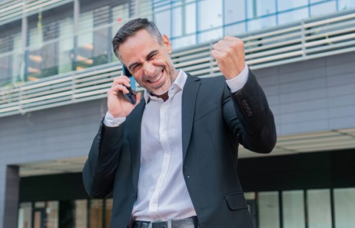 رجل مبتسم يرتدي بدلة سوداء اللون ويتحدث بالهاتف