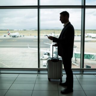 رجل يمسك حقيبة سفر بيده وينتظر في المطار