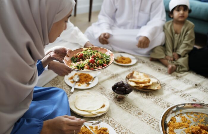 امرأة محجبة تقوم بسكب الطعام لأفراد العائلة في رمضان