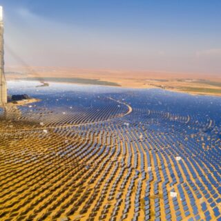 مجموعة من الألواح العاكسة لأشعة الشمس موزعة بشك دائري كبير يعكس الضوء نحو قمة برج معدني موجود في منتصف هذا الحقل