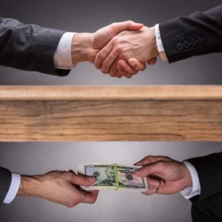 تصافح الأيدي فوق الطاولة وتبادل الأموال تحت الطاولة