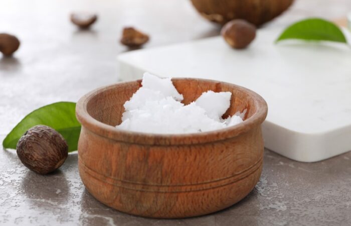 بذور بنية اللون وزبدة الشيا بيضاء اللون ضمن وعاء خشبي