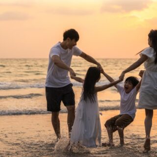 أب و أم مع طفليهما يلعبون على شاطئ البحر عند المغيب