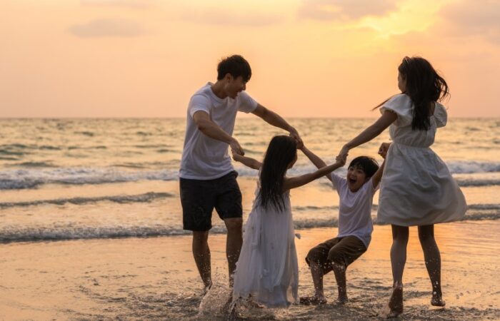 أب و أم مع طفليهما يلعبون على شاطئ البحر عند المغيب