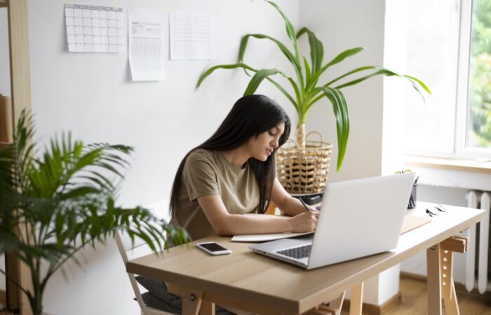 امرأة تجلس على الكرسي وجهاز حاسوب على الطاولة أمامها