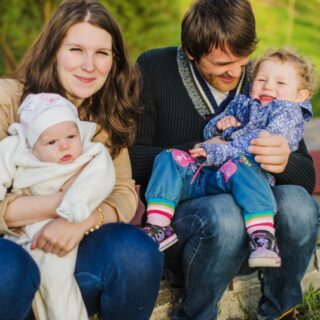 رجل وامرأة يجلسون بجانب بعضهم البعض ويحملون بين أيديهم اطفال صغار