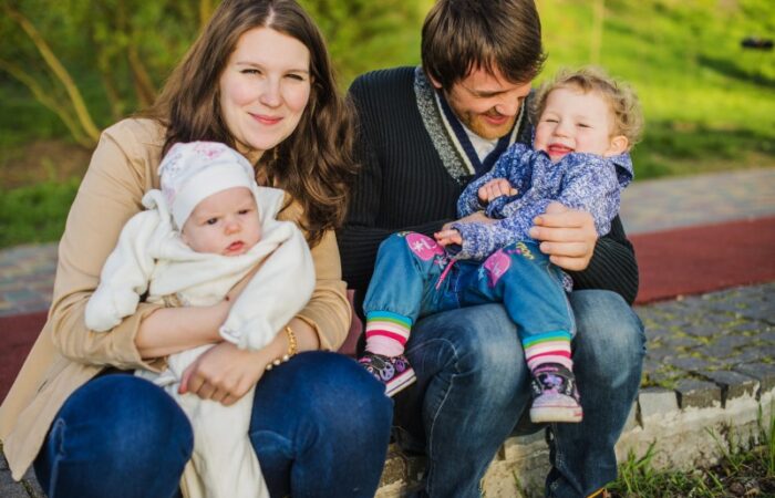 رجل وامرأة يجلسون بجانب بعضهم البعض ويحملون بين أيديهم اطفال صغار