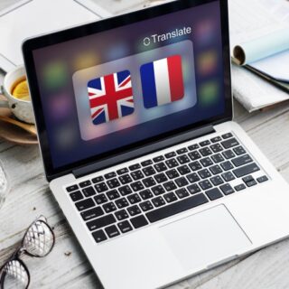 لابتوب مرسوم على شاشته علم بريطانيا وفرنسا ومكتوب أعلى الشاشة كلمة translate