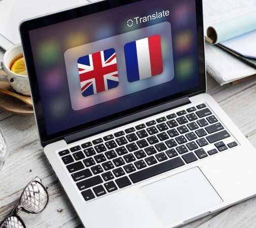 لابتوب مرسوم على شاشته علم بريطانيا وفرنسا ومكتوب أعلى الشاشة كلمة translate